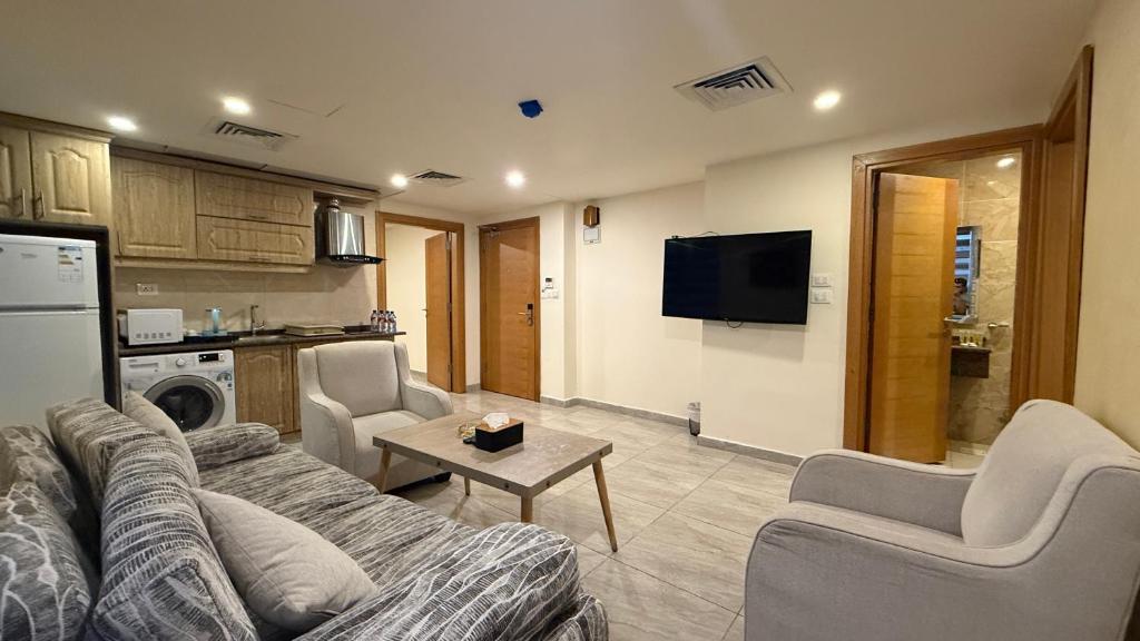a living room with a couch and chairs and a tv at Jawheret S Hotel Suite in Amman