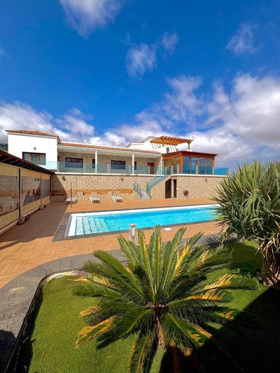 a house with a swimming pool and a palm tree at Villa en el Time con piscina in Puerto del Rosario