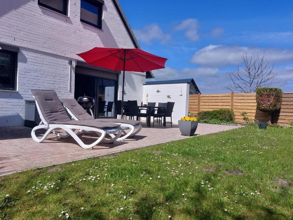 a patio with a chair and a red umbrella at Haus Schwalbennest in Dahme