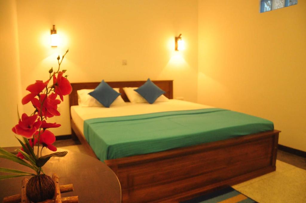 a bedroom with a bed with a table and flowers at Era Guest House in Unawatuna