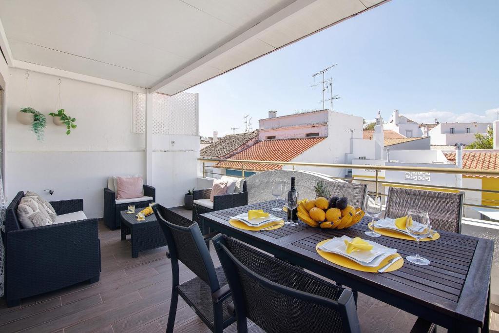 a dining table with a bowl of fruit on a balcony at Flor de Sol House in Tavira