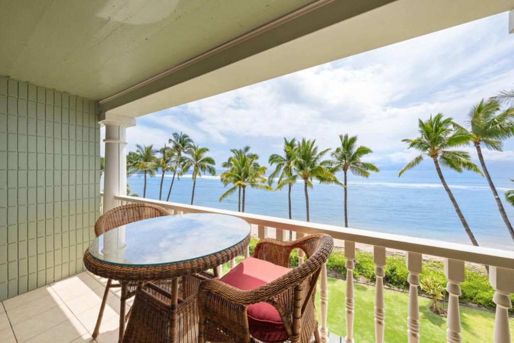a balcony with a table and chairs and the ocean at Maui Beachfront Haven 433 in Lahaina