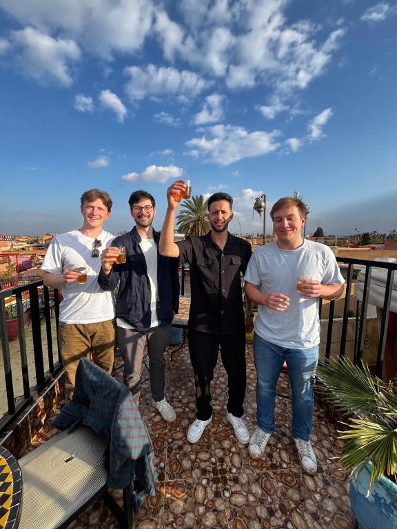 a group of men standing on a balcony holding drinks at Riad Jennah Rouge in Marrakesh