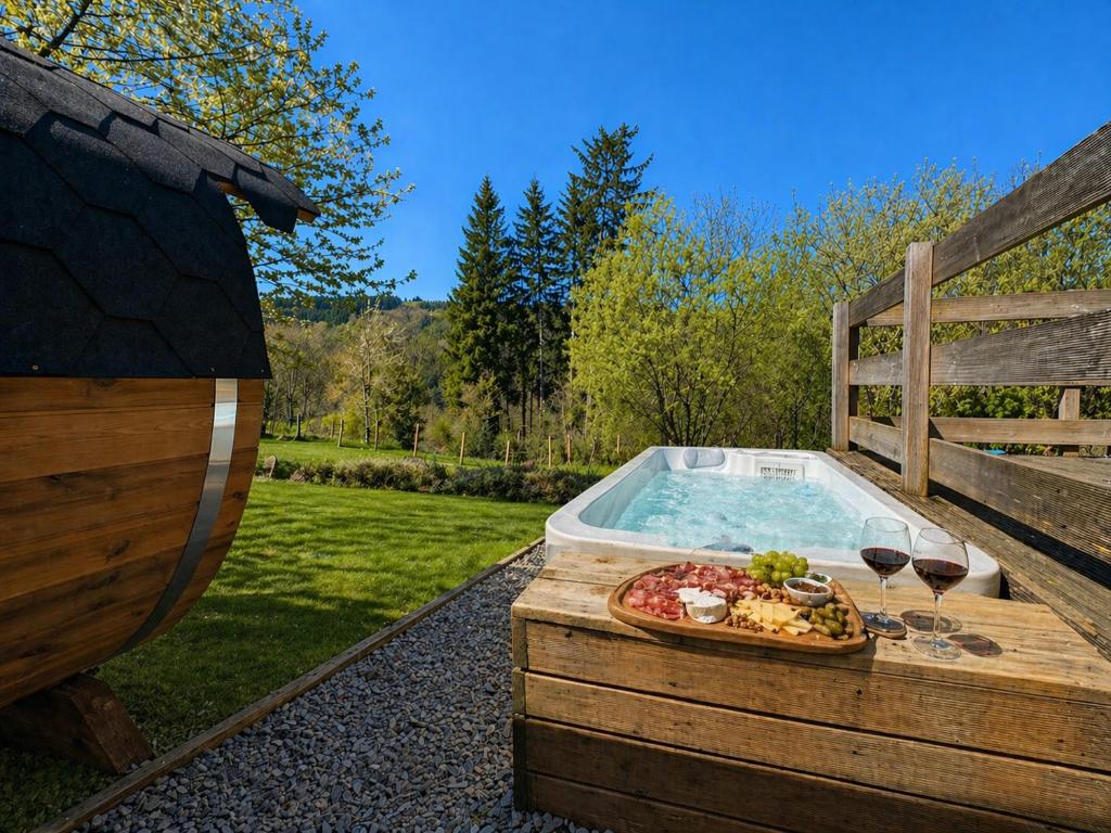 ein Whirlpool mit einem Teller Essen und Gläsern Wein in der Unterkunft Chaly in Stoumont