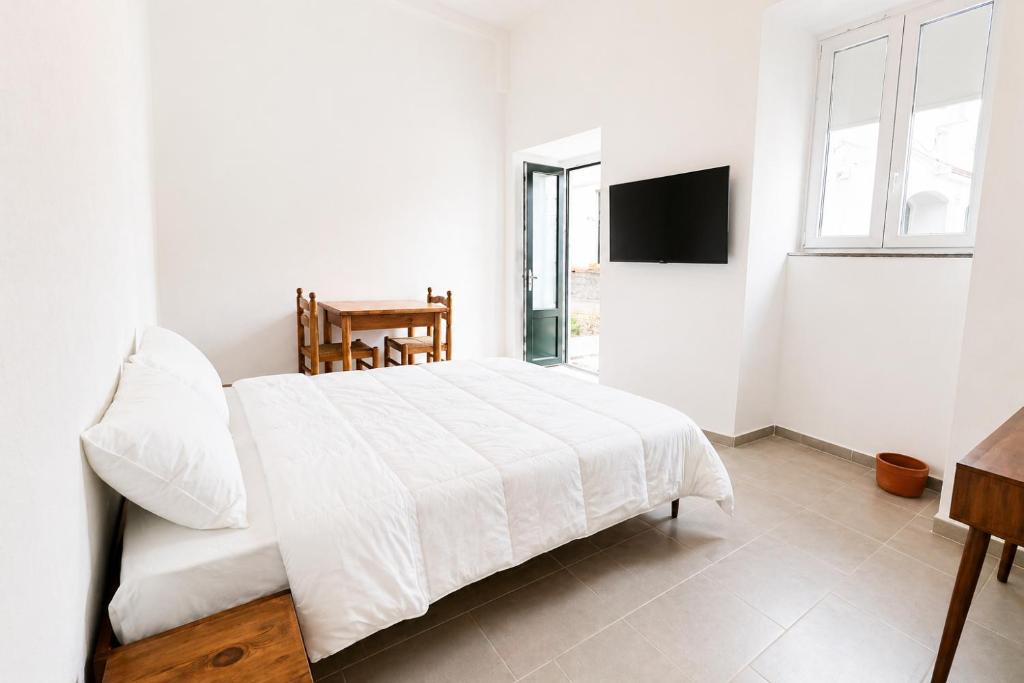 a bedroom with a white bed and a television at Casa Leonardo in Casamicciola Terme