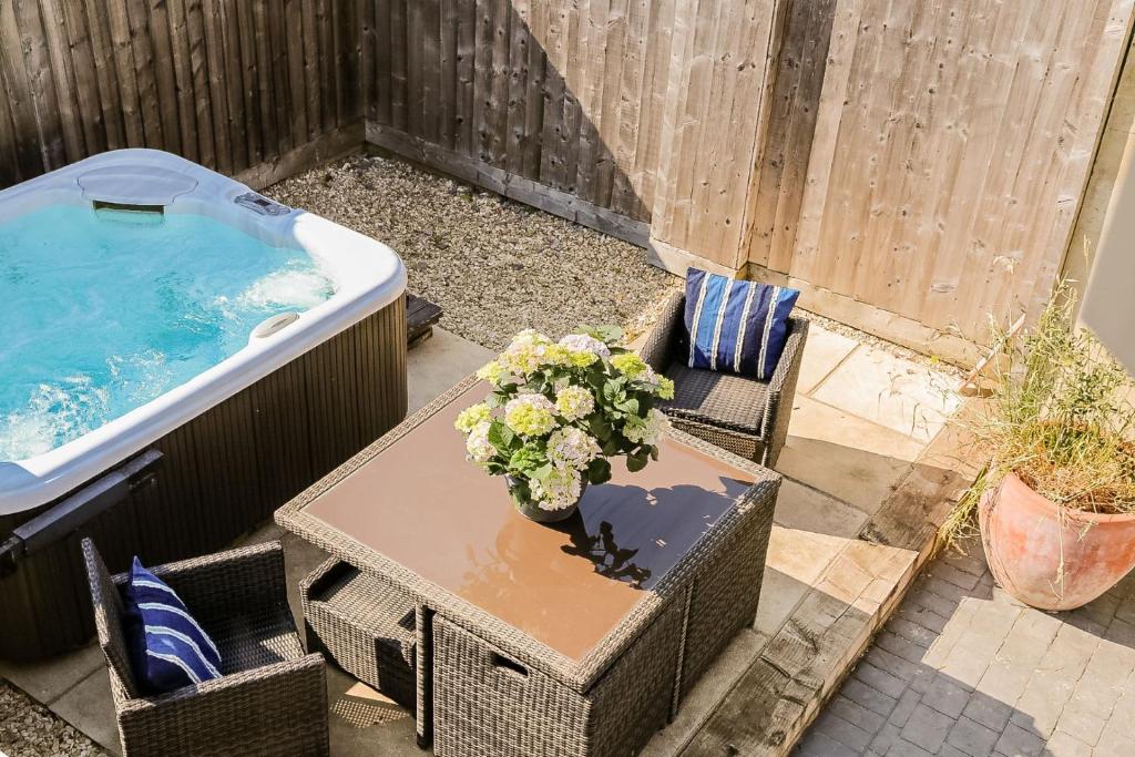 a table with a vase of flowers next to a bath tub at King's Cottage in Wootton