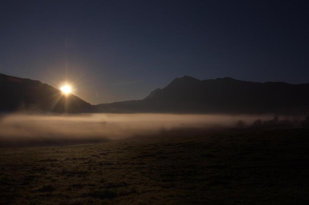 a foggy field with the sun rising over mountains at Landhotel Binderhäusl in Inzell
