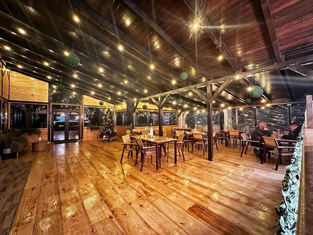 a dining room with tables and chairs on a wooden floor at Pensiunea La Cuscrii in Arad
