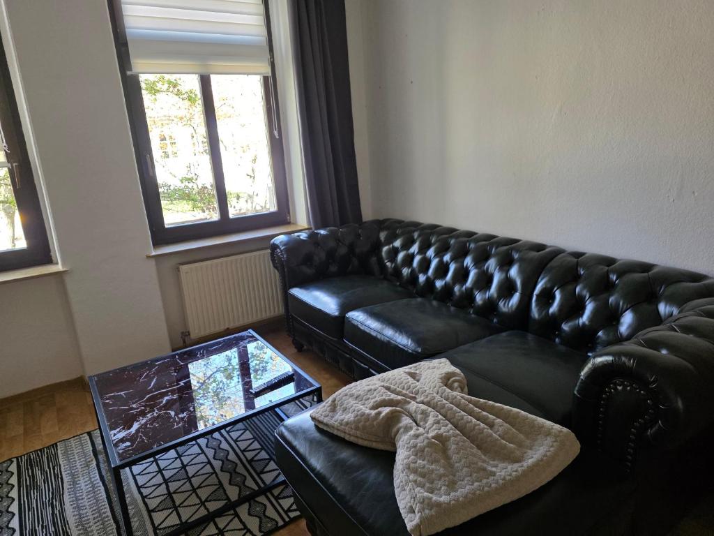 a living room with a black leather couch and a table at FEWO Civrilli 1 Zeitz in Zeitz