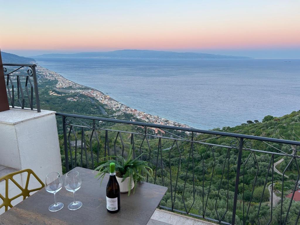 a table with wine glasses on top of a balcony at Domus Mea, Case Vacanza Vista Mare vicino Taormina in Forza dʼAgro