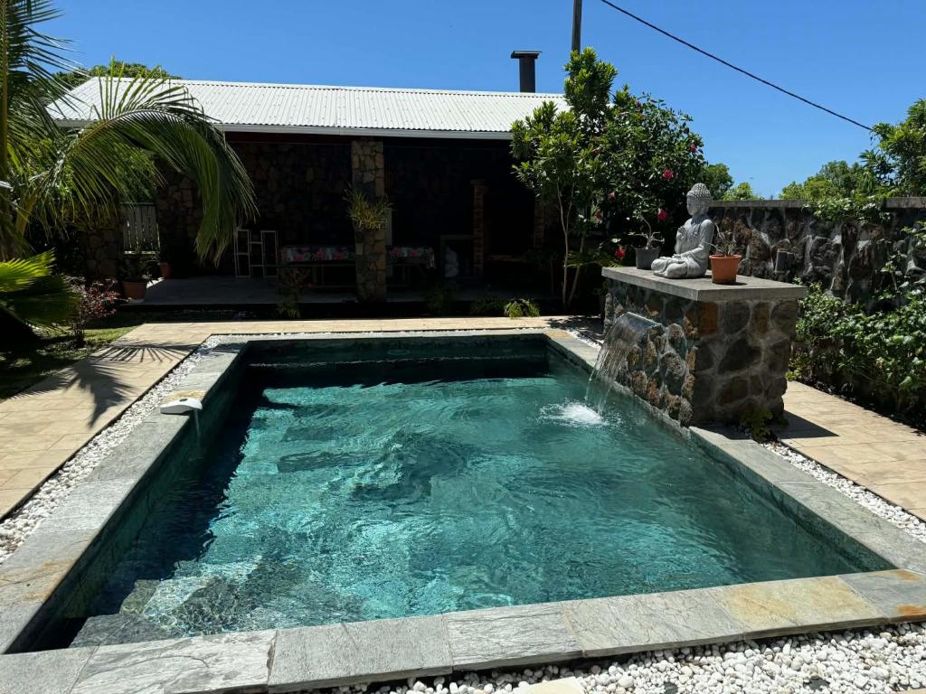 a swimming pool in a yard with a statue in it at Villa oasis des laves in Sainte-Rose