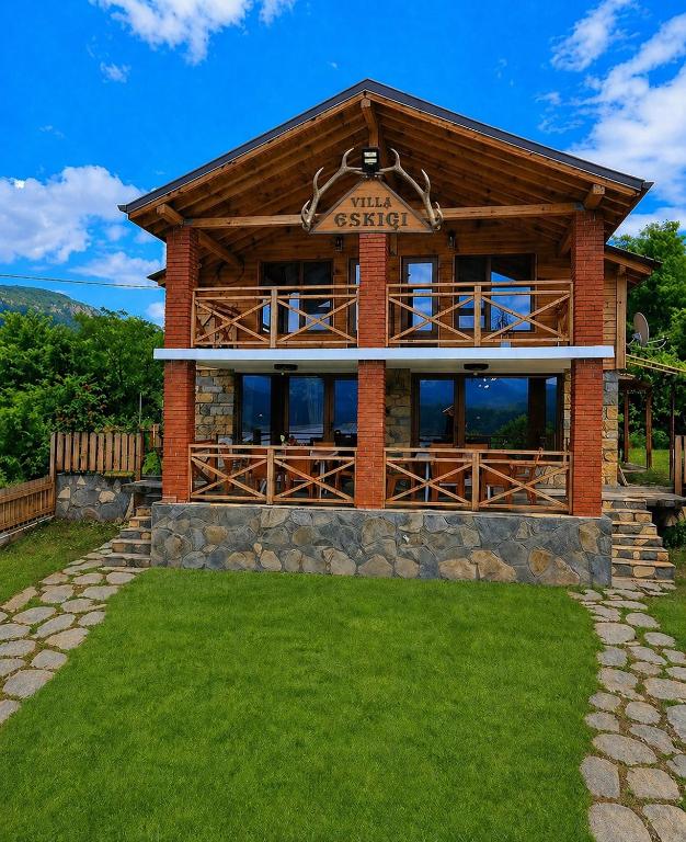 a log cabin with a green lawn in front of it at Villa Eskici in Staro Myasto
