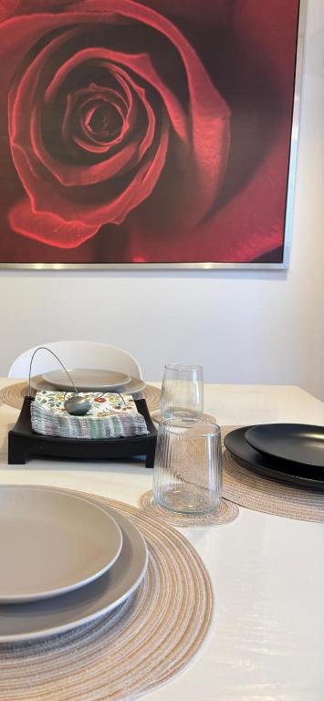 a table with plates and a painting of a rose at MIALLEGRA Guest House in Bellona