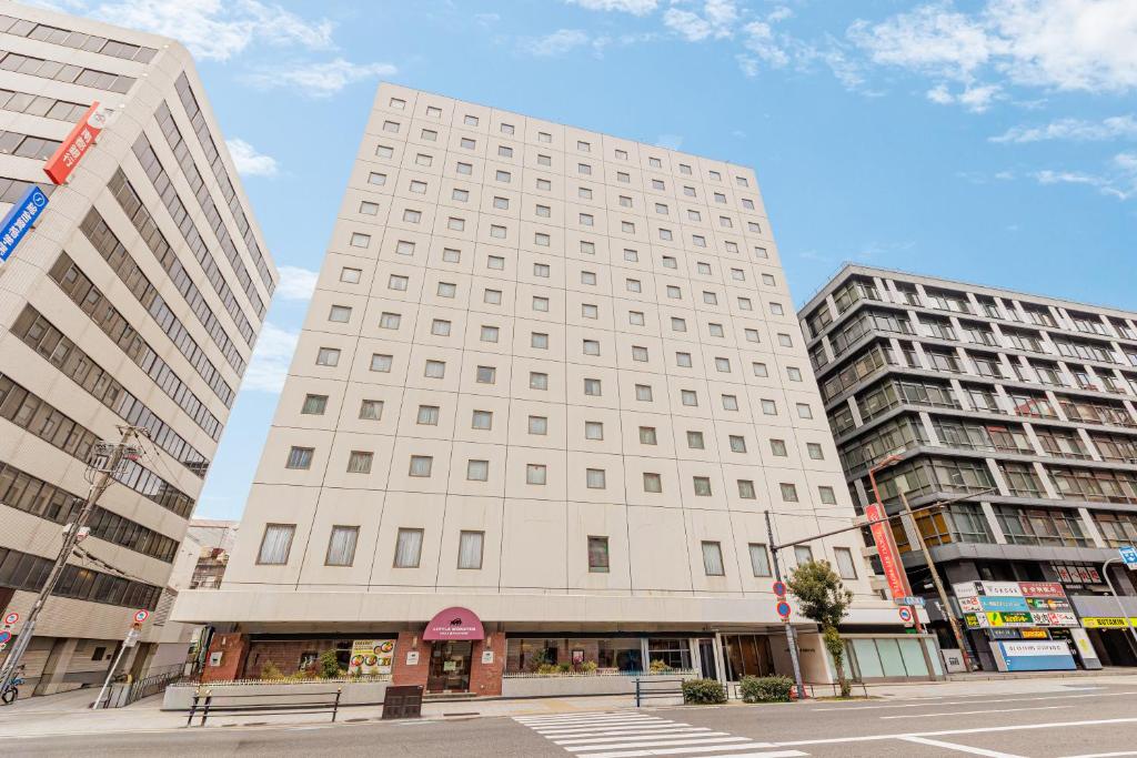 a tall white building with two tall buildings at Osaka Tokyu REI Hotel in Osaka