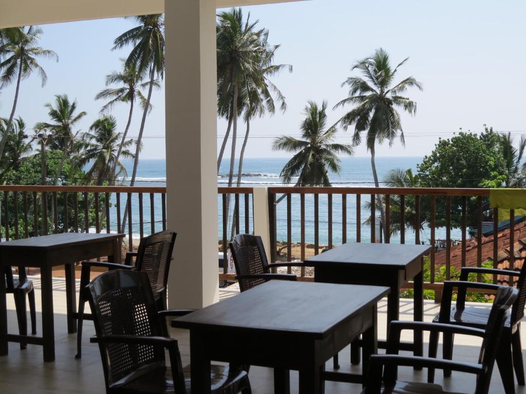 une terrasse avec des tables et des chaises et la plage dans l'établissement Sailors Mirissa, à Mirissa