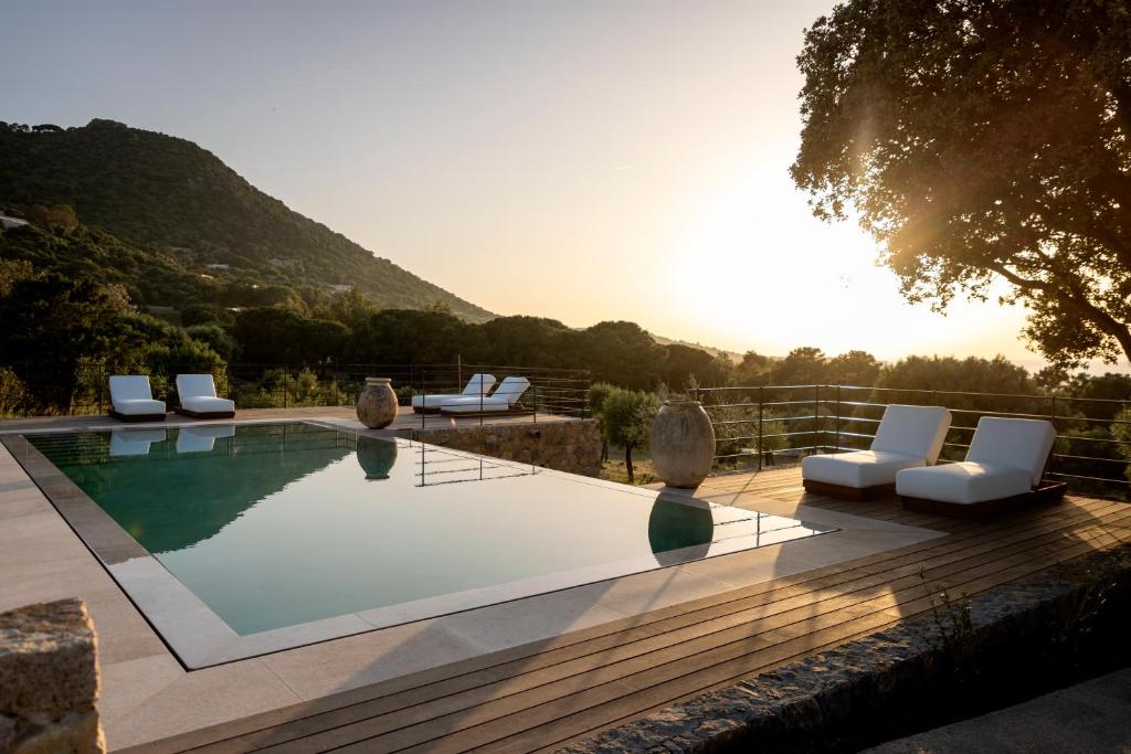 a swimming pool with white chairs at Les Paillers de Bodri - Vue mer et piscine - Adults Only in Corbara