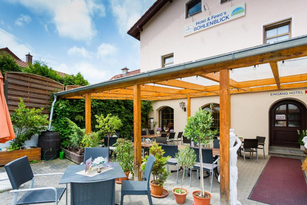 a patio with tables and chairs in front of a building at Hotel & Ferienwohnungen Bohlenblick in Saalfeld