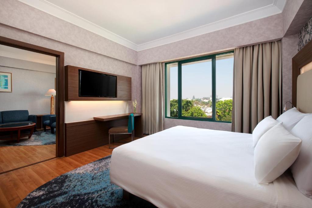 a hotel room with a large bed and a window at Novotel Solo in Solo