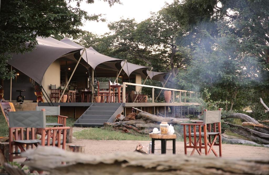 a group of tables and chairs and a building with smoke at Chamabondo Luxury Tented Camp in Victoria Falls
