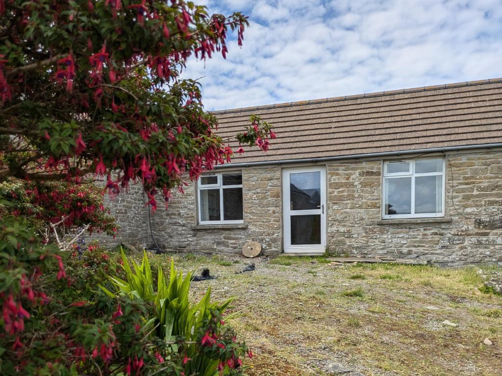 a brick house with white windows and a tree at Rousay&nbspCottage in Orkney