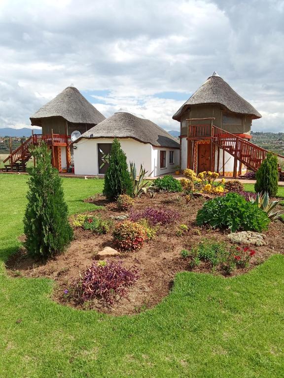 two huts with thatched roofs in a yard at Qbela in Phuthaditjhaba