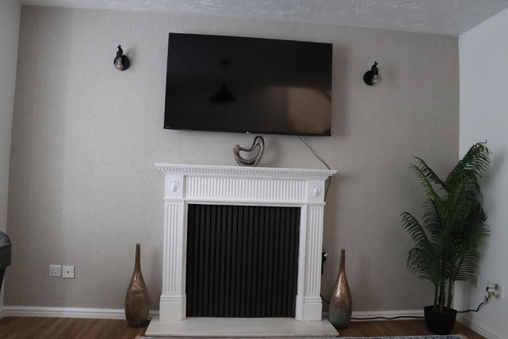 a living room with a fireplace with a television above it at The Wigmore house in Luton