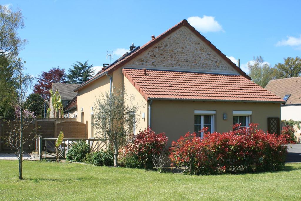 une maison avec un toit rouge dans une cour dans l'établissement Les cottages de Magny, à Magny-les-Hameaux