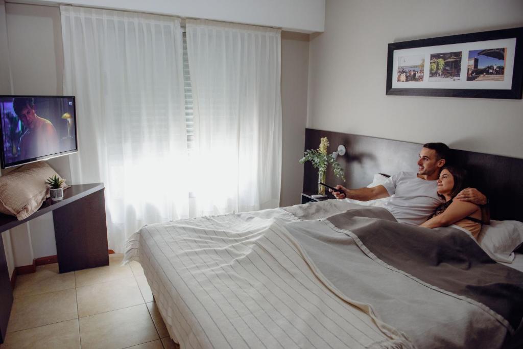 a man and a woman laying in bed watching tv at Rosario Temporal in Rosario
