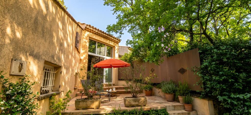 a patio with an orange umbrella and some plants at Clos du Veyrier in Bédoin