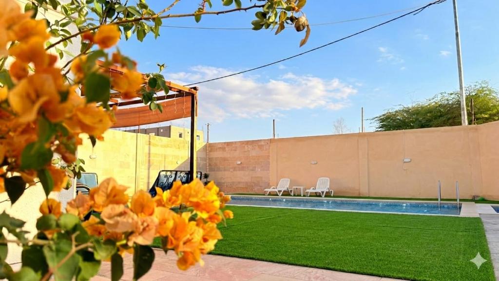 a backyard with a swimming pool and orange flowers at Entire Home Near Deadsea & Baptism Site Pool, Garden, BBQ, Great Price in Shūnat Nimrīn