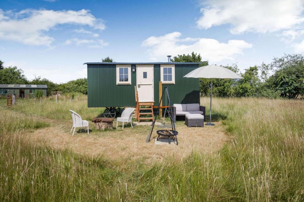 a green and white tiny house in a field at Littlestock Shepherds Hut in Shipton under Wychwood