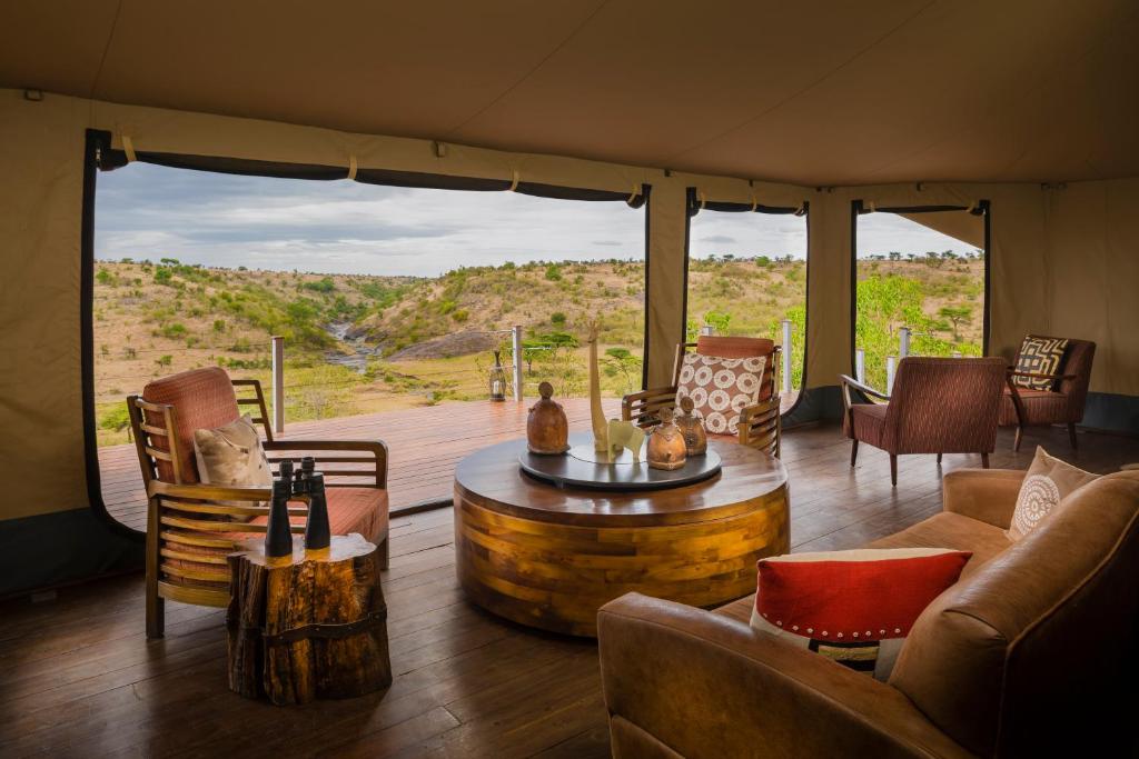 ein Wohnzimmer mit einem Tisch und Stühlen in einem Zelt in der Unterkunft Mahali Mzuri in Aitong