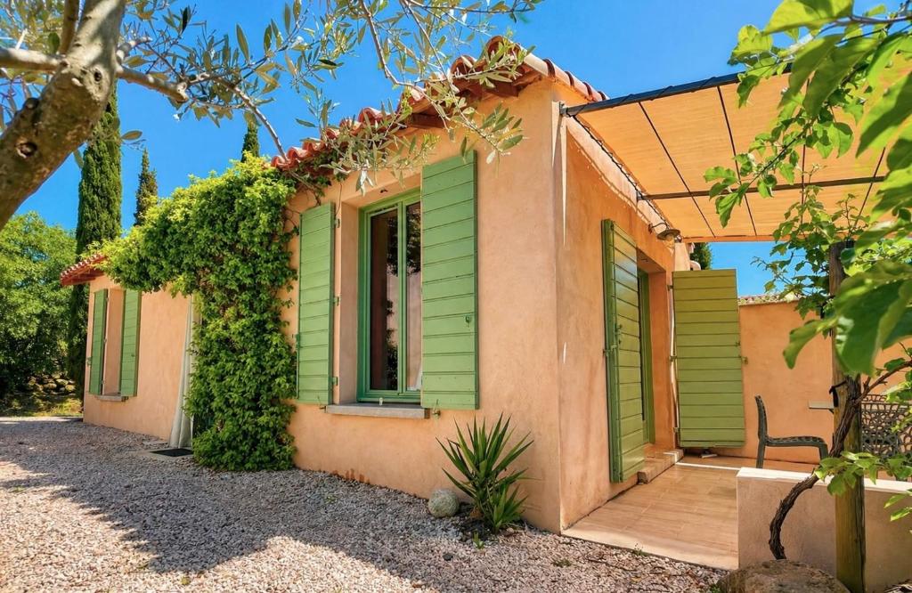 a house with green shutters on the side of it at Gîte du salagou in Octon