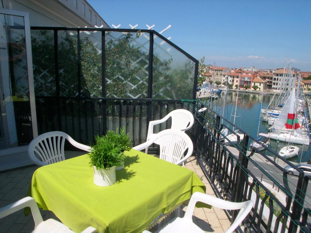 a green table and white chairs on a balcony at San Marco Appartament in Grado