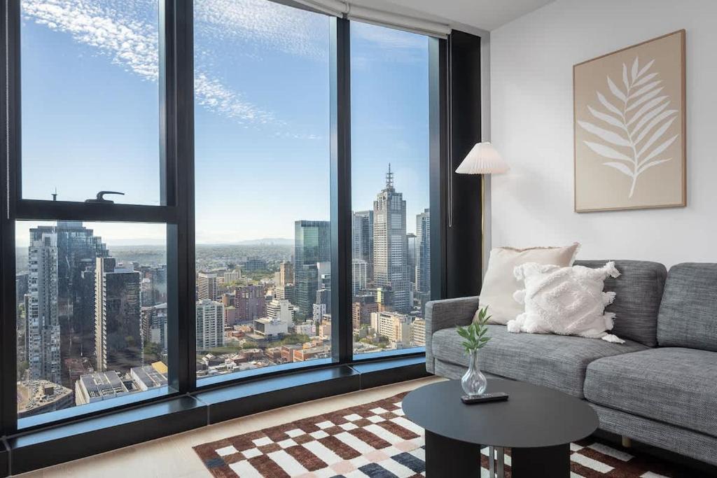a living room with a couch and large windows at LaneStay - 2BR Panoramic Views w Pool Spa & Gym in Melbourne