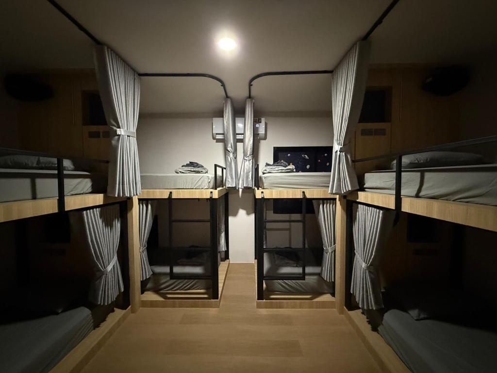 a room with two bunk beds and a desk at Jupiter Hostel in Ban Khlong Haeng