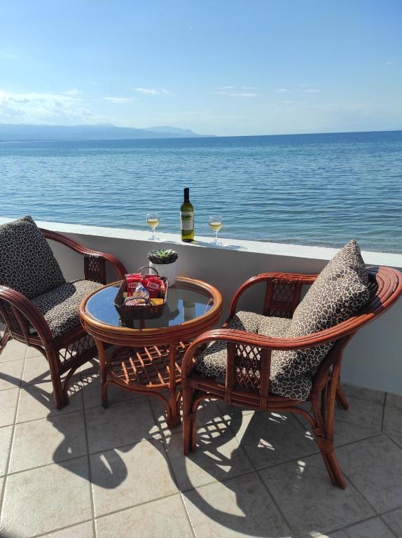 eine Terrasse mit Stühlen und einem Tisch mit Weingläsern in der Unterkunft On The Waves Suites in Korinthos