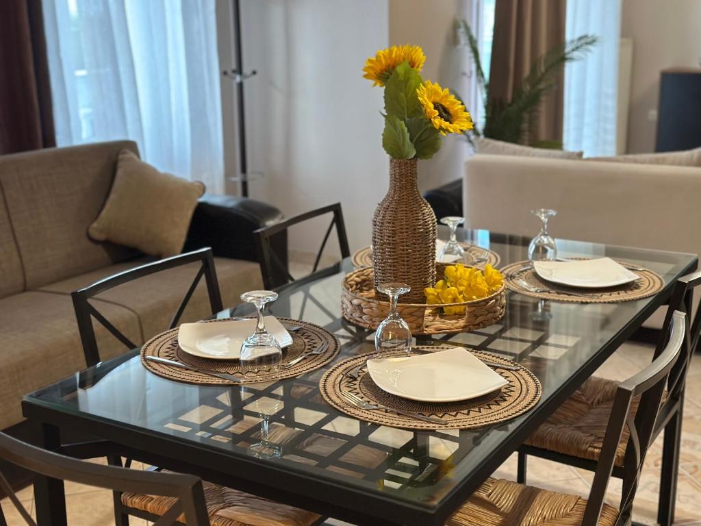 a glass table with two plates and a vase with flowers at Complex Summer Memories Souzan in Keramoti