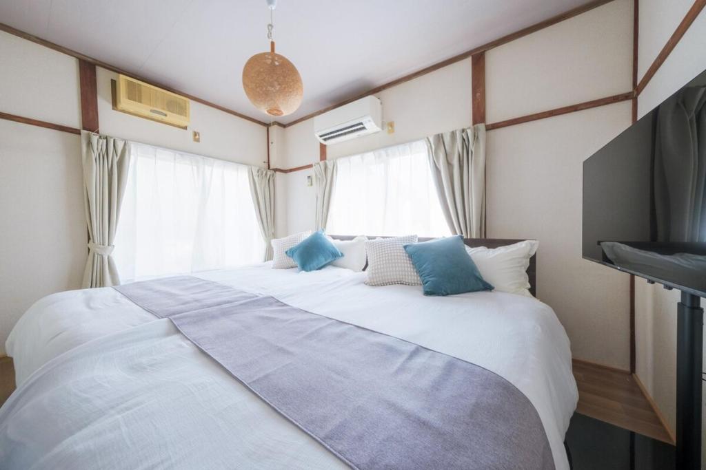 a bedroom with a large white bed with blue pillows at KEI HOUSE Yamato 101 in Yamato