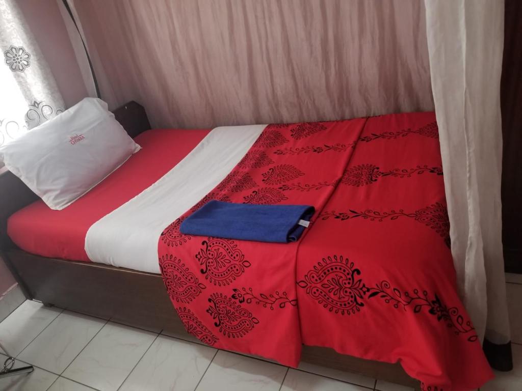 a bed with a red and white comforter at Chumber Hotel in Gatunga