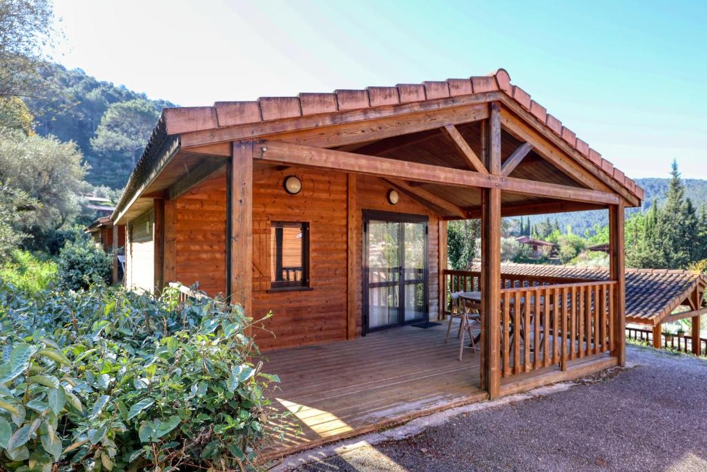a wooden cabin with a deck with a table at L'Oasis provençale - Joli chalet avec terrasse in Solliès-Toucas