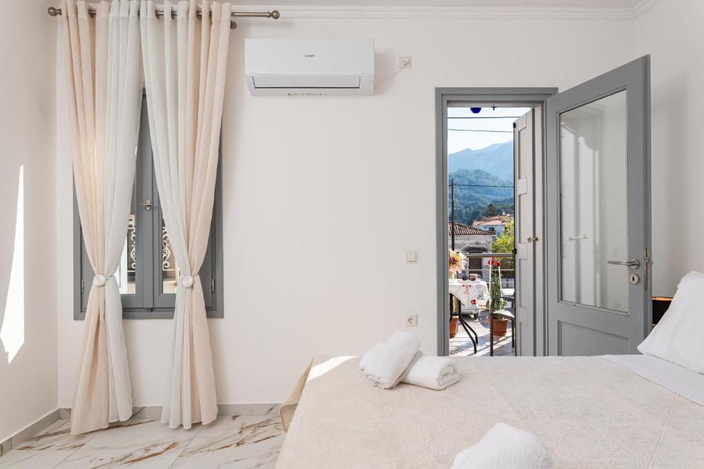 a white bedroom with a bed and a balcony at Villa Leta in Kokkari