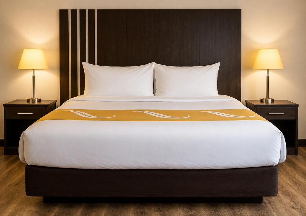 a large bed in a hotel room with two lamps at Village Inn & Suites in Sarnia