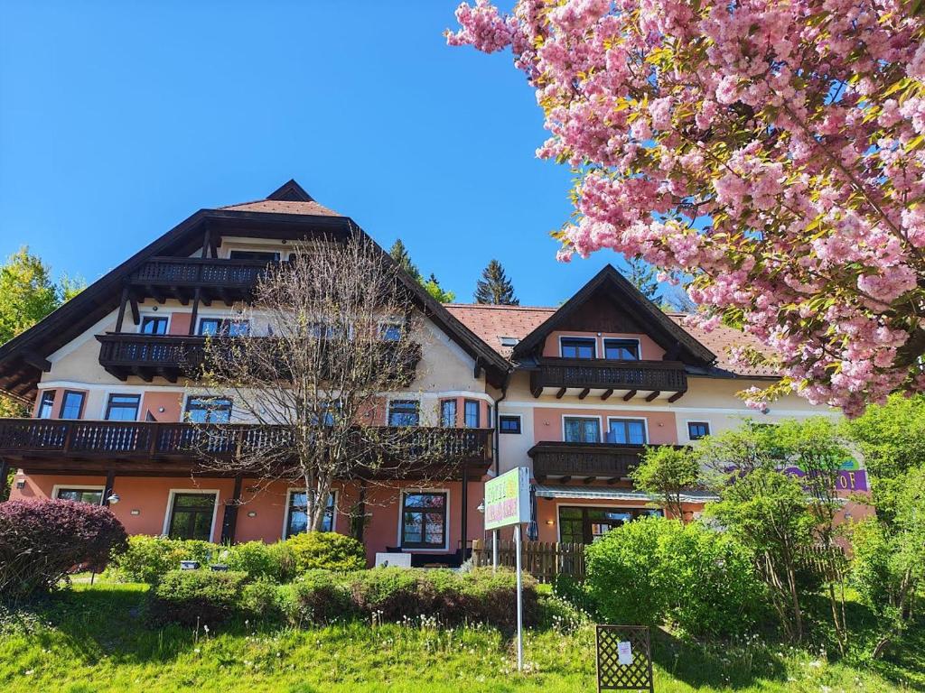 a building with a flowering tree in front of it at Hotel Kärntnerhof Velden - Zum Schankbaron in Velden am Wörthersee
