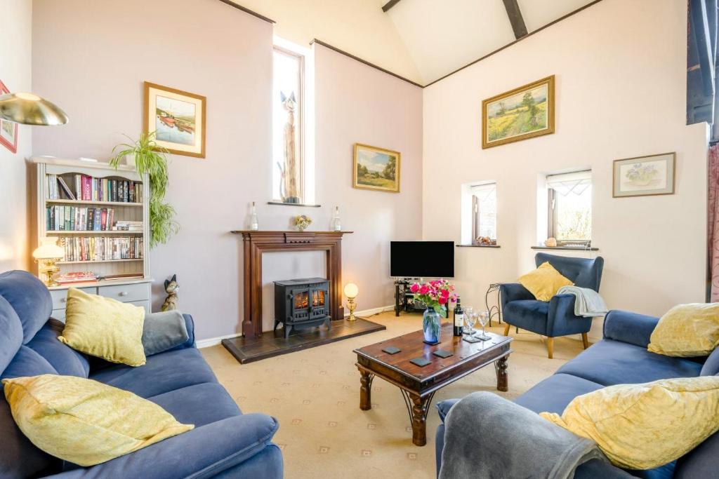 a living room with blue couches and a fireplace at 3 Bed in Little Ellingham oc-2147 in Rockland Saint Peter