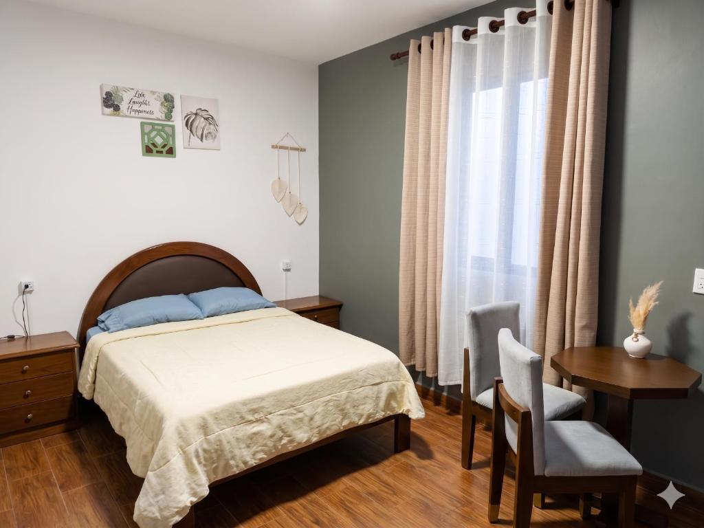 a bedroom with a bed and a table and a chair at Tu Refugio de Descanso a Pasos de Todo in Cochabamba