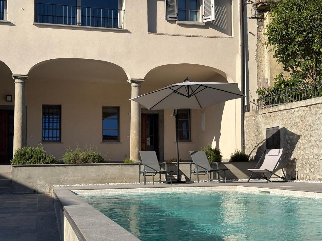 a pool with chairs and an umbrella next to a house at Dimora Federica in Erbusco