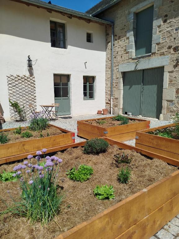 a garden with wooden raised beds in front of a building at Terre de Plaisirs in Forgès