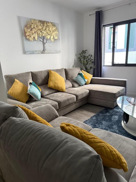 a living room with a gray couch and yellow pillows at Grannies House in Machico