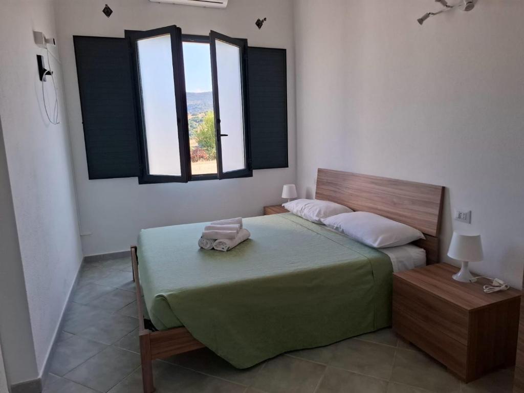 a bedroom with a bed and two windows at Su Debieddu Rooms in Solità